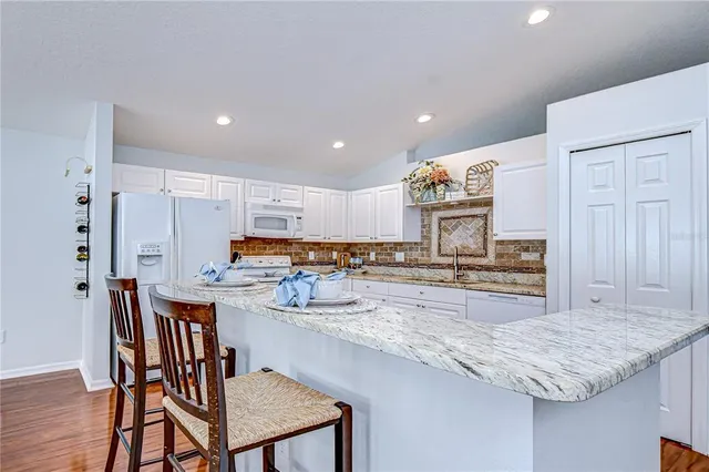 a kitchen with stainless steel appliances granite countertop a table chairs sink and cabinets