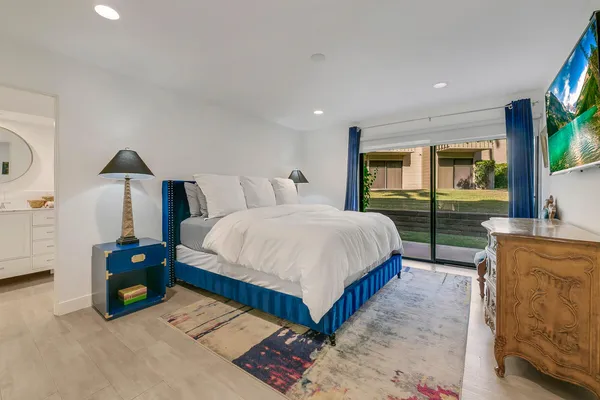 a bedroom with a bed and a flat tv screen on dresser