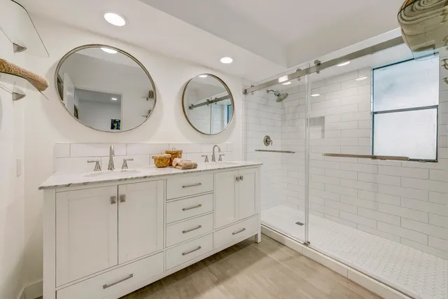 a bathroom with a double vanity sink mirror and shower