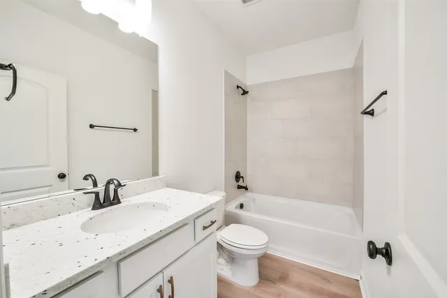 a bathroom with a granite countertop sink a toilet and shower