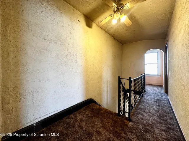 a view of a hallway with wooden floor and chandelier