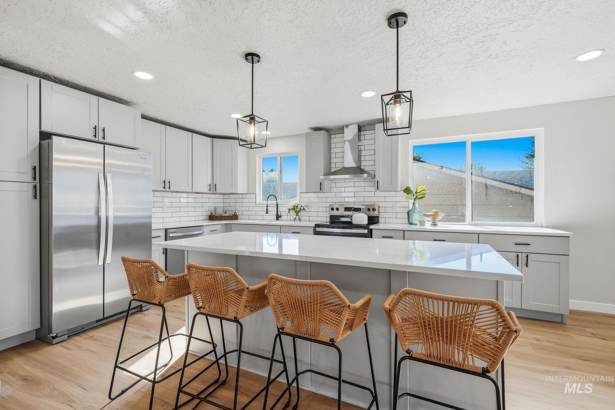 1990 Panama Street Boise, ID 83705 - Photo 21 of 50 Bright kitchen featuring light gray cabinetry, stainless steel appliances, a center island with seating, a subway tile backsplash, and wood-finish flooring
