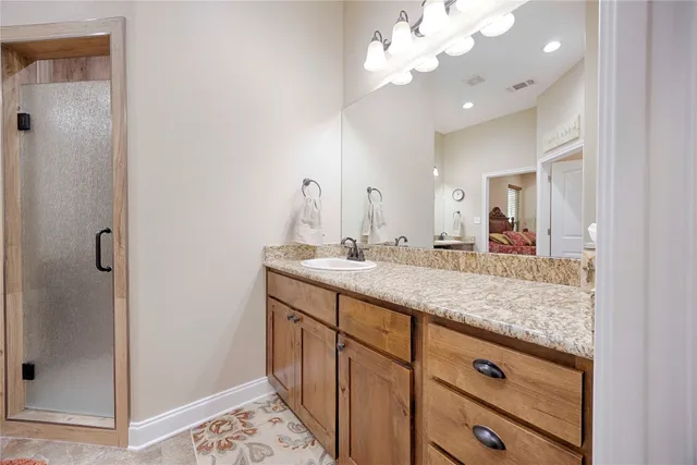 a bathroom with a granite countertop sink a toilet a mirror and shower