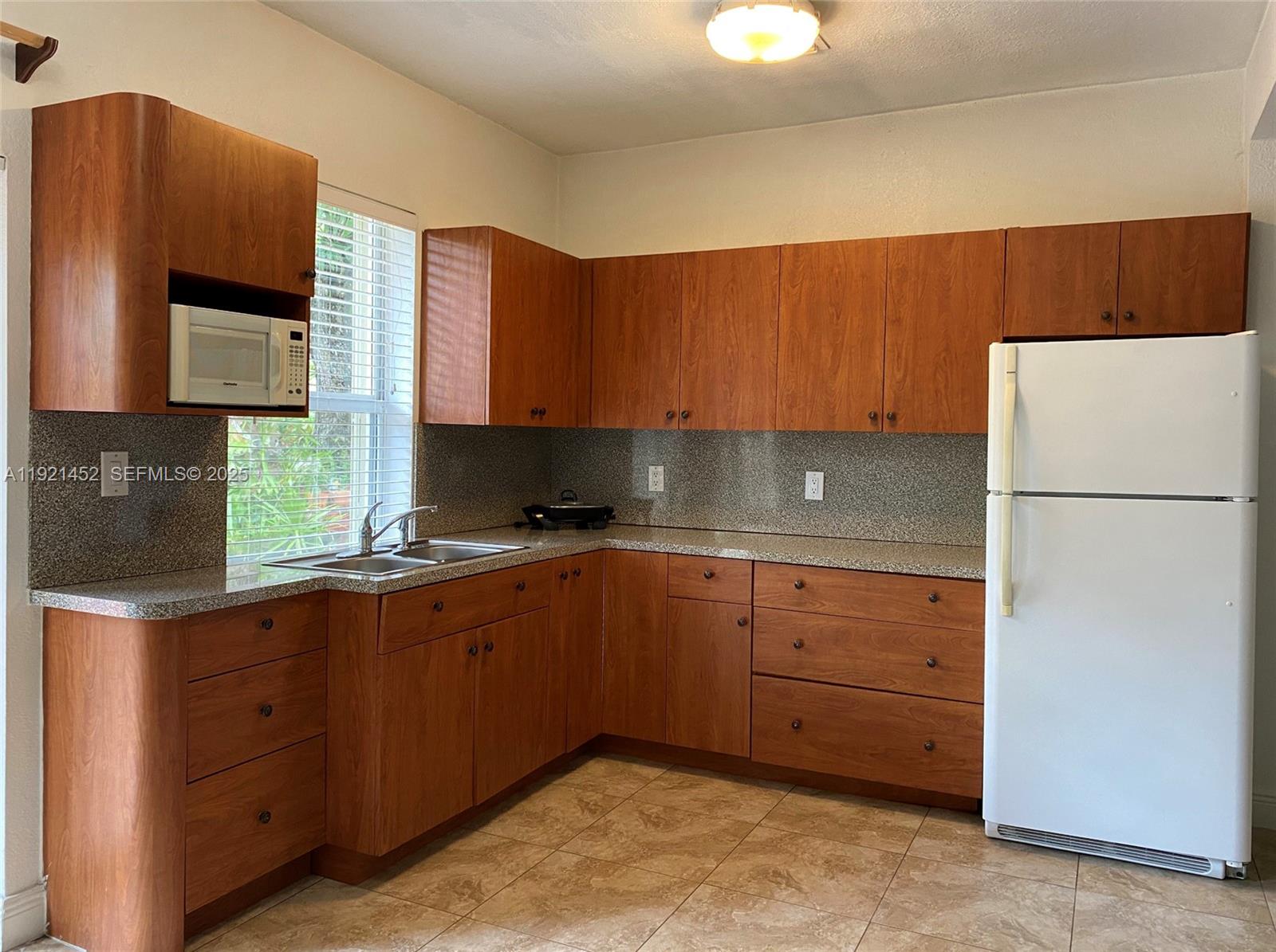 7880 Southwest 14th Terrace Miami, FL 33144 - Photo 43 of 43 a kitchen with sink a refrigerator and cabinets