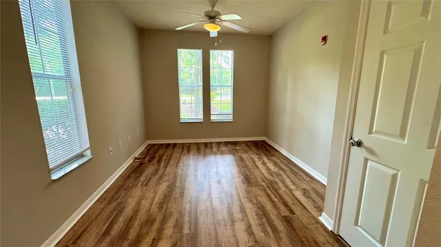a view of an empty room with wooden floor and a window
