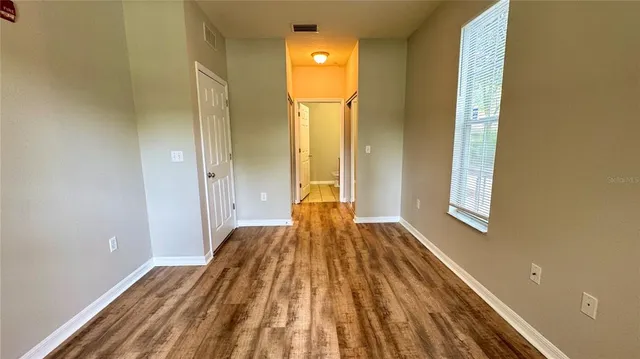 a view of a bedroom with wooden floor and windows