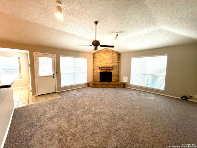 an empty room with windows and fireplace