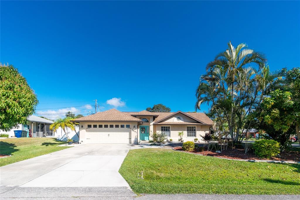 a view of a white house with a big yard plants and large trees