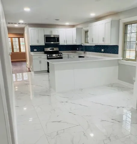 a kitchen with kitchen island white cabinets and stainless steel appliances