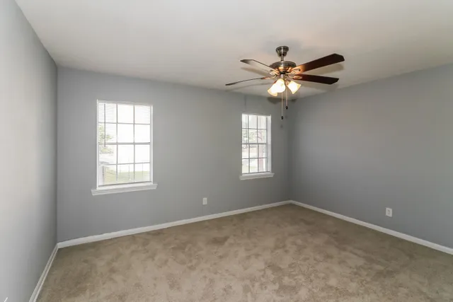 a view of a room with windows and chandelier fan