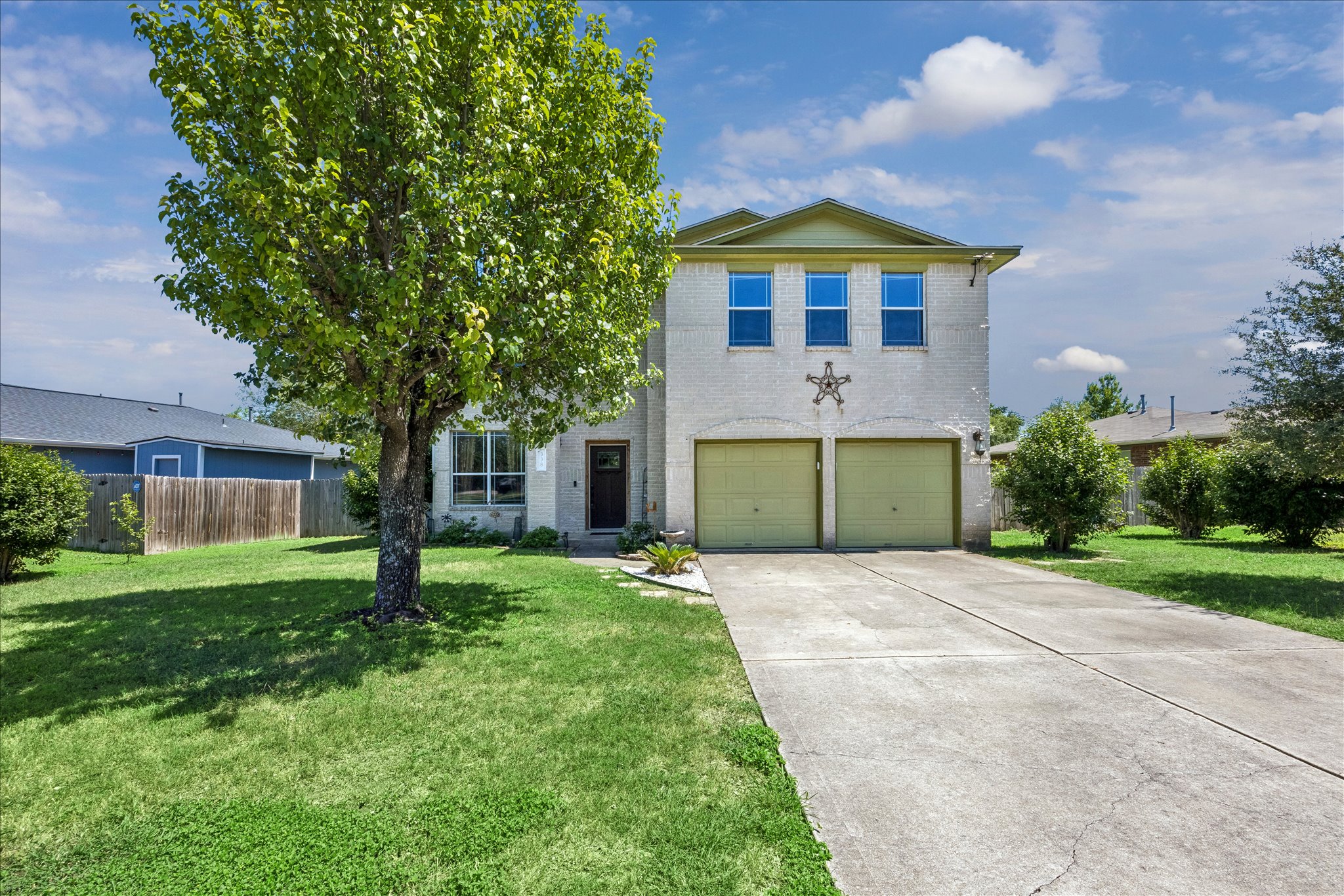 A classic brick exterior with a two-car garage awaits, set against a verdant lawn.
