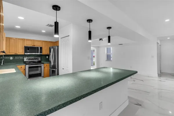 a kitchen with granite countertop a stove sink and microwave