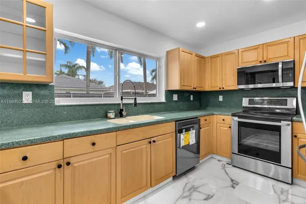 a kitchen with stainless steel appliances granite countertop a refrigerator a stove and a sink with wooden cabinets