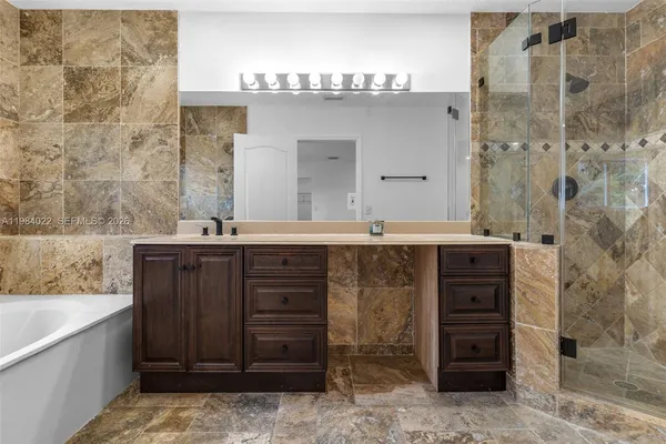 a bathroom with a tub a sink double vanity and a mirror