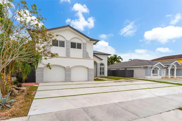 a white building with a large tree in front