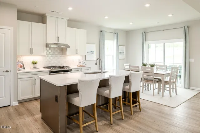 a kitchen with stainless steel appliances a white table and chairs