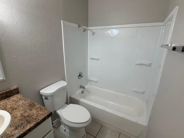 a bathroom with a granite countertop toilet and a shower