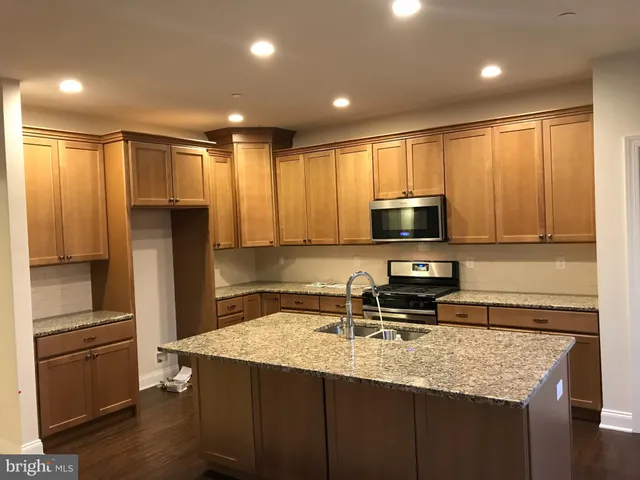 a kitchen with kitchen island granite countertop a stove refrigerator and microwave