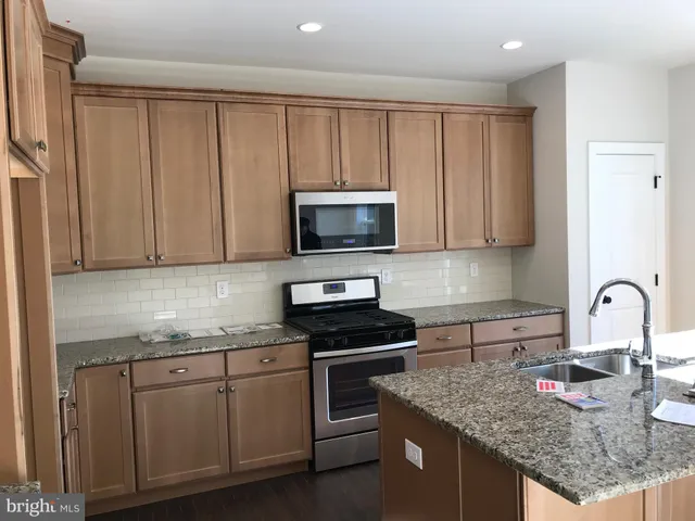 a kitchen with granite countertop a sink and a stove top oven with wooden floor