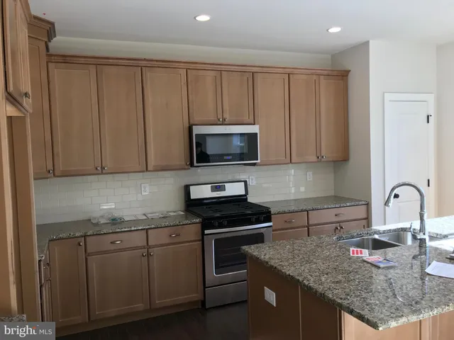 a kitchen with granite countertop white cabinets and stainless steel appliances