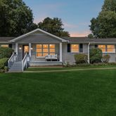 a front view of a house with a yard and green space