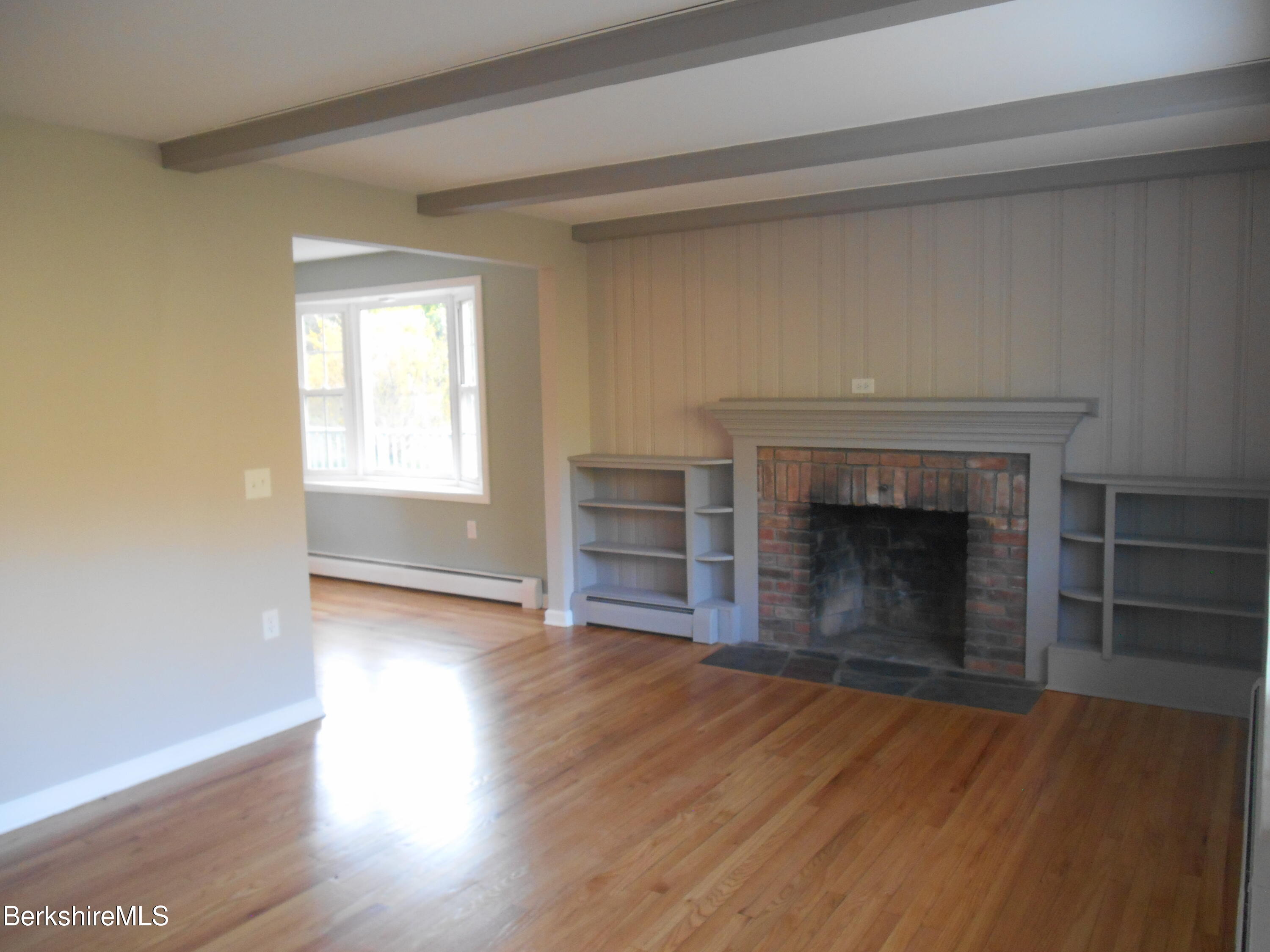 238 Swamp Road Richmond, MA 01201 - Photo 7 of 21 an empty room with wooden floor fireplace and windows