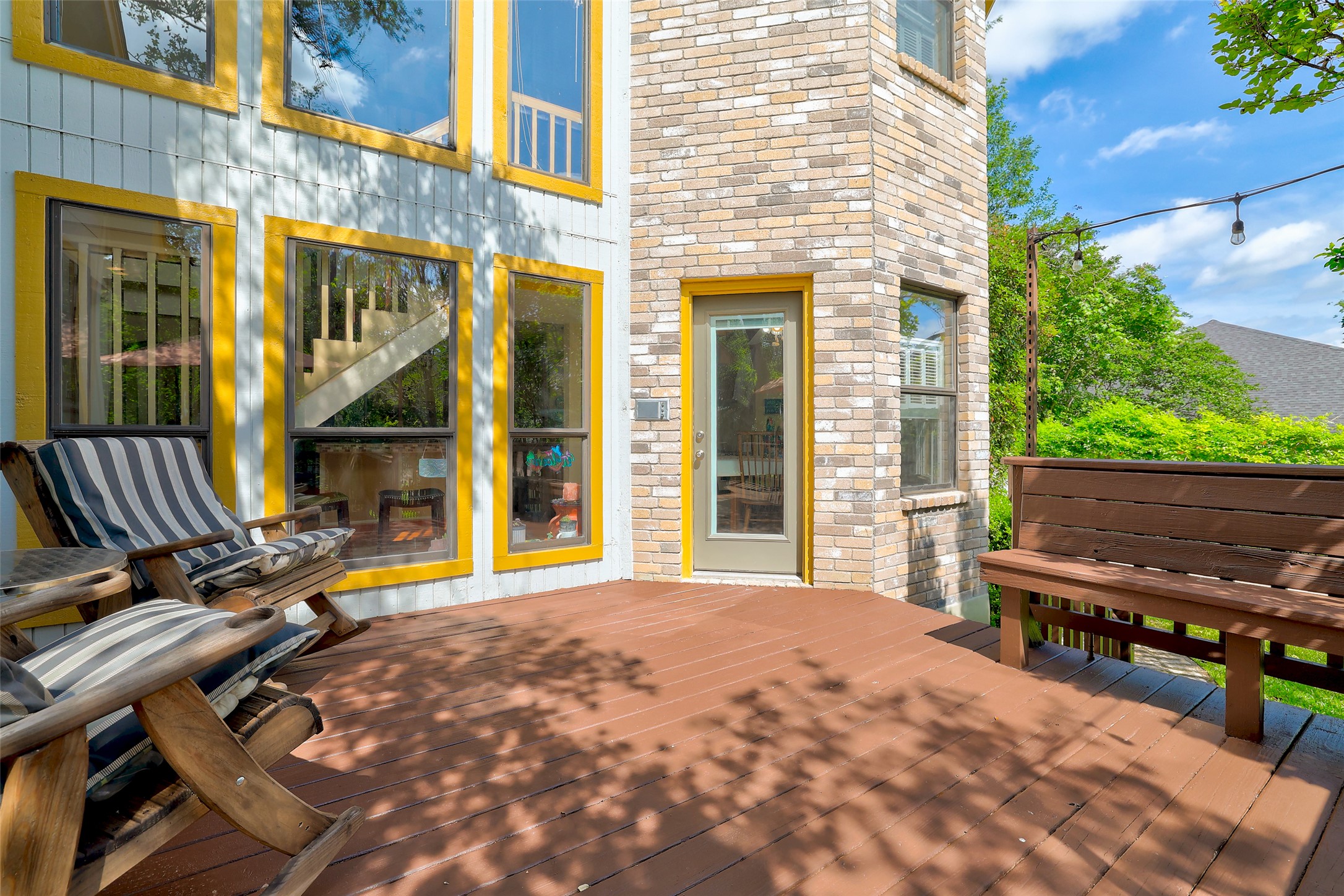 110 South Ridge Circle Georgetown, TX 78628 - Photo 30 of 37 Expansive wood-finish deck with a built-in bench, featuring a brick exterior and multiple large windows with yellow trim