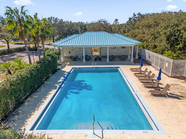 a view of swimming pool with lawn chairs under an umbrella