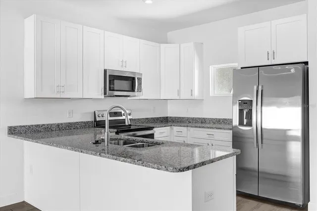 a kitchen with stainless steel appliances granite countertop a sink a refrigerator and a granite counter tops