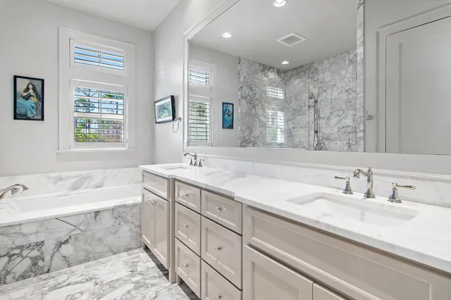 a bathroom with a sink double vanity granite tub shower and a mirror
