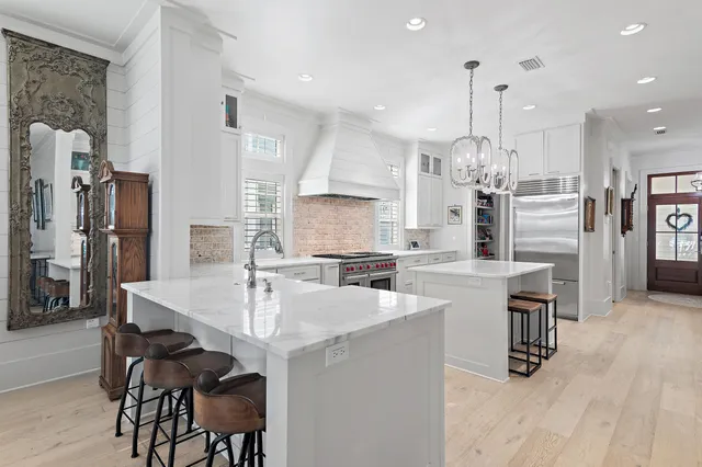 a kitchen with stainless steel appliances kitchen island granite countertop a table chairs and a refrigerator