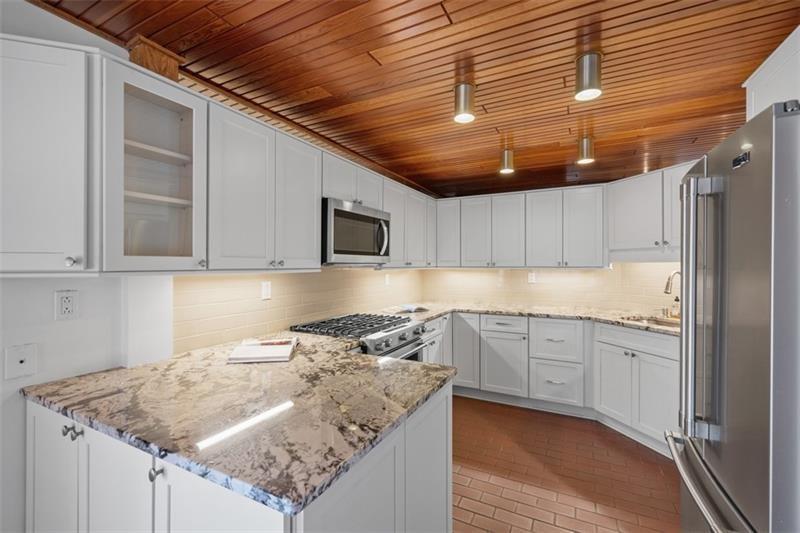 5 Bayard Road, Unit 219 Pittsburgh, PA 15213 - Photo 8 of 26 Overhead lighting accentuates the rich wood-toned ceilings, creating a warm, inviting, and truly distinctive kitchen space.