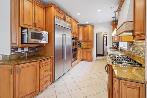 a large kitchen with kitchen island granite countertop a large window and white cabinets