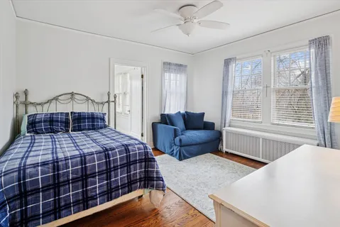 a bedroom with a bed and a large window with wooden floor