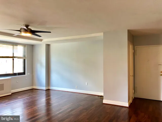 a view of an empty room with wooden floor and a window