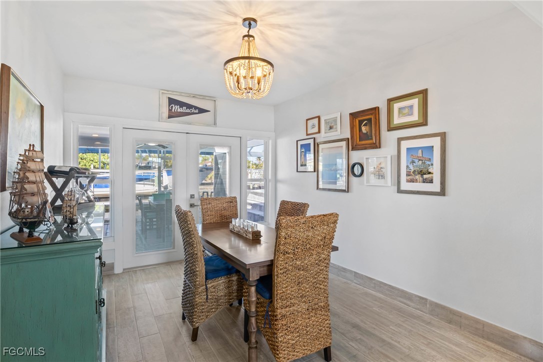 2556 Cay Cove Matlacha, FL 33993 - Photo 11 of 44 a dining room with wooden floor a chandelier a wooden table and chairs