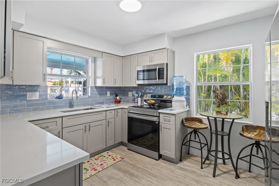 2556 Cay Cove Matlacha, FL 33993 - Photo 14 of 44 a kitchen with stainless steel appliances granite countertop a stove top oven a sink dishwasher a dining table and chairs with wooden floor