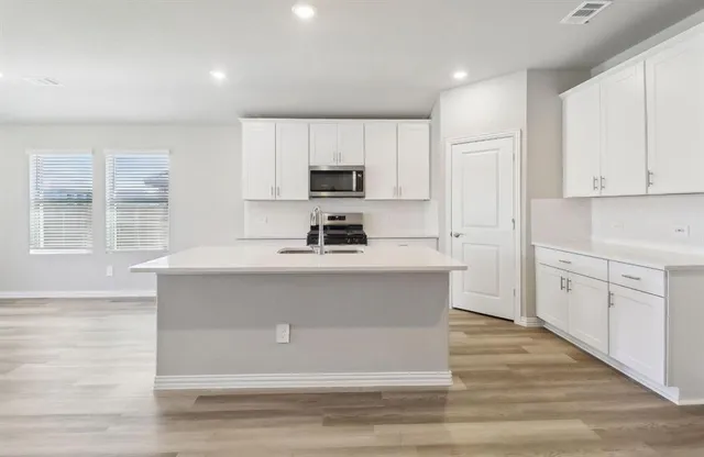 a kitchen with kitchen island white cabinets and stainless steel appliances