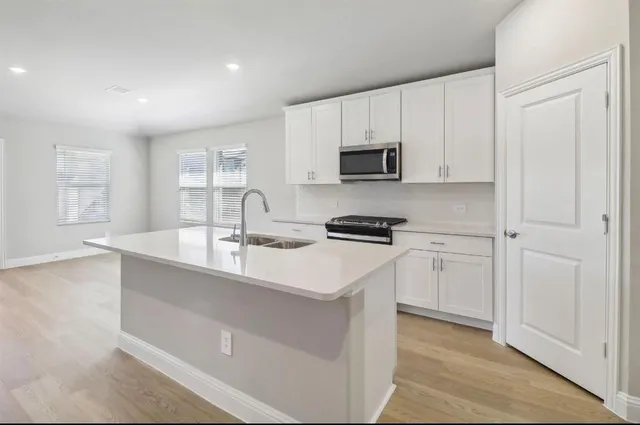 a kitchen with white cabinets and black appliances