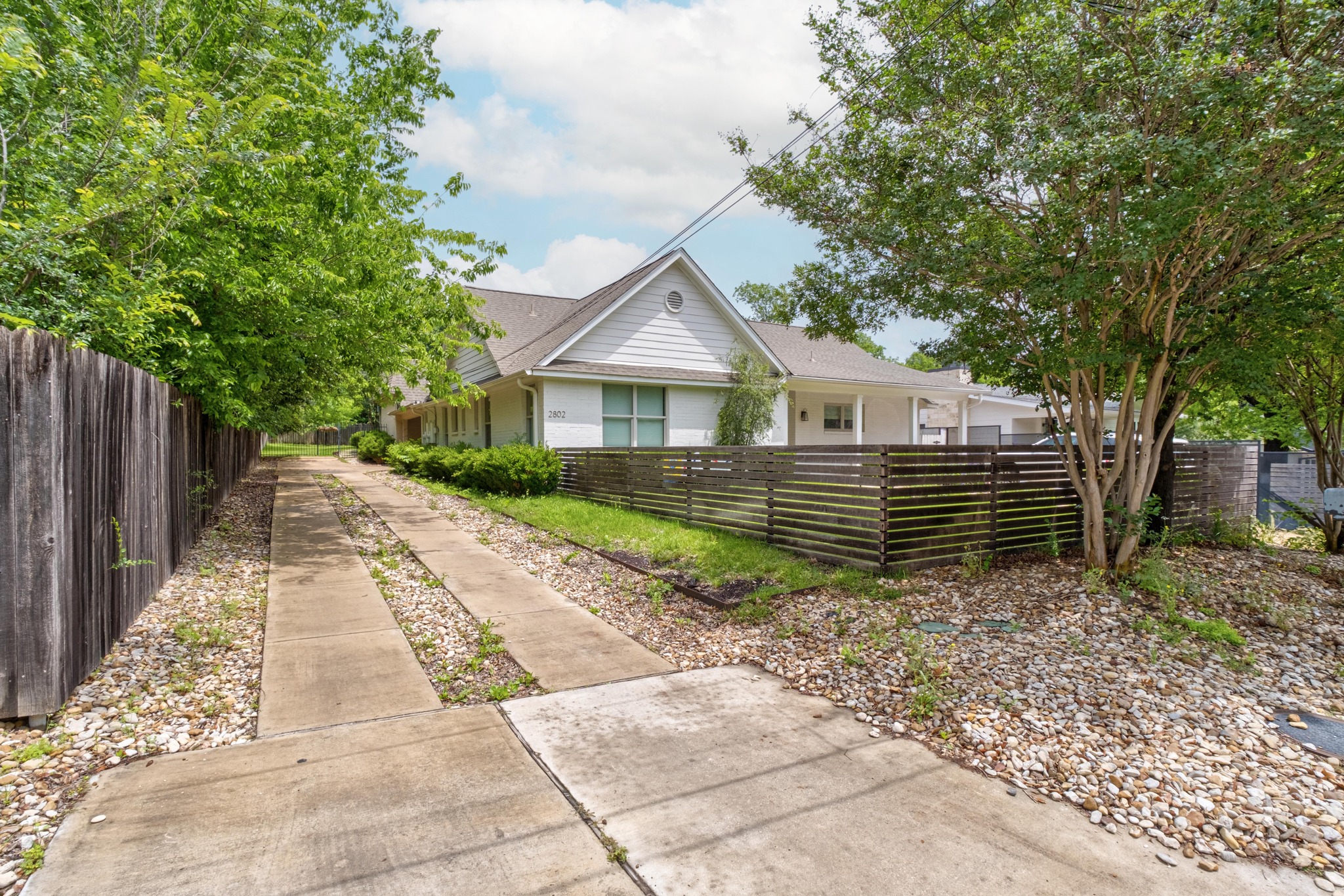 White siding residence with a gabled roofline and horizontal slat fencing