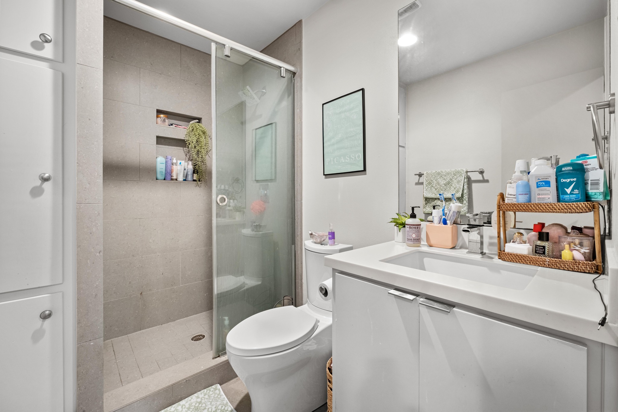 2802 Warren Street, Unit B Austin, TX 78703 - Photo 17 of 23 Bathroom featuring a glass-enclosed shower with tile surround, built-in shower niches, a white vanity with an integrated sink, and a large wall-mounted mirror