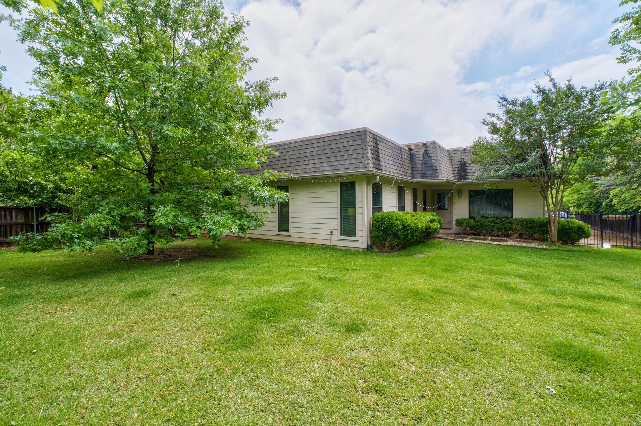2802 Warren Street, Unit B Austin, TX 78703 - Photo 21 of 23 Front exterior featuring a gambrel roofline, cream-colored siding, and a spacious front lawn