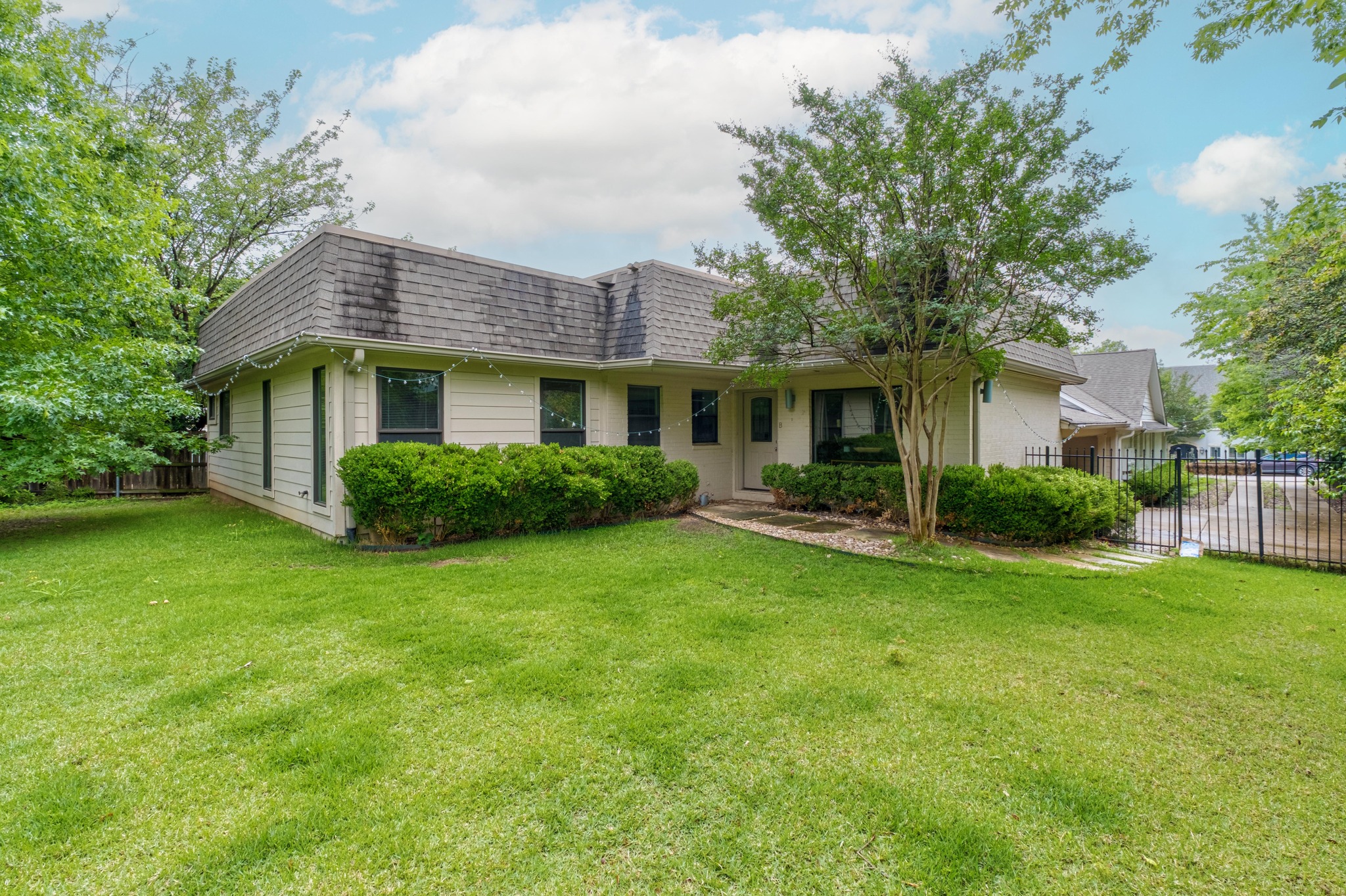 2802 Warren Street, Unit B Austin, TX 78703 - Photo 22 of 23 Property exterior featuring a light-colored facade, dark shingle roof, and established landscaping