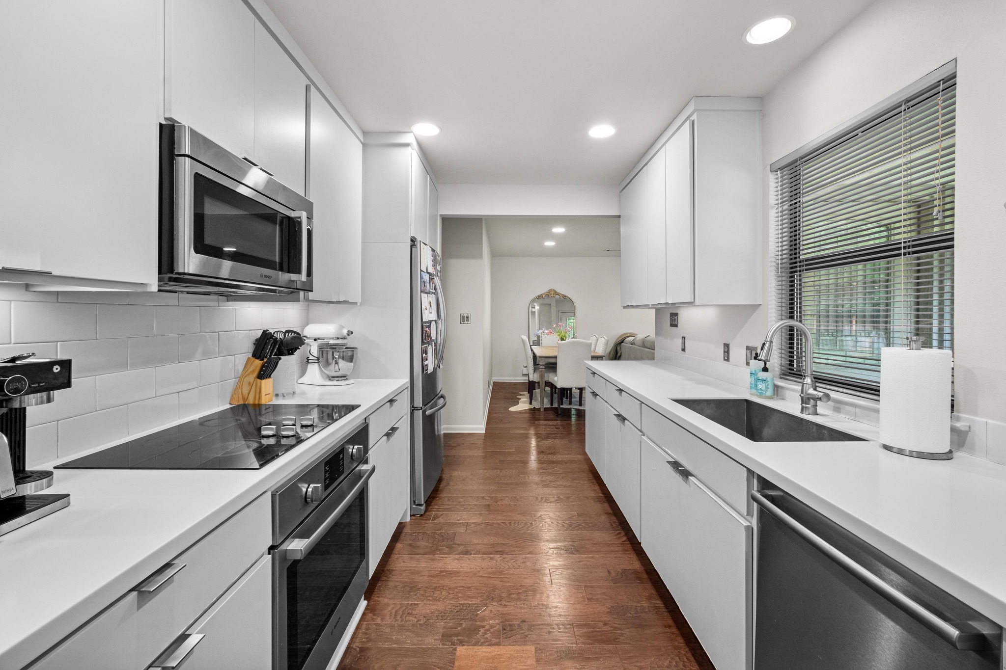 2802 Warren Street, Unit B Austin, TX 78703 - Photo 6 of 23 Galley kitchen featuring white cabinetry, stone countertops, stainless steel appliances, tile backsplash, and wood-finish flooring