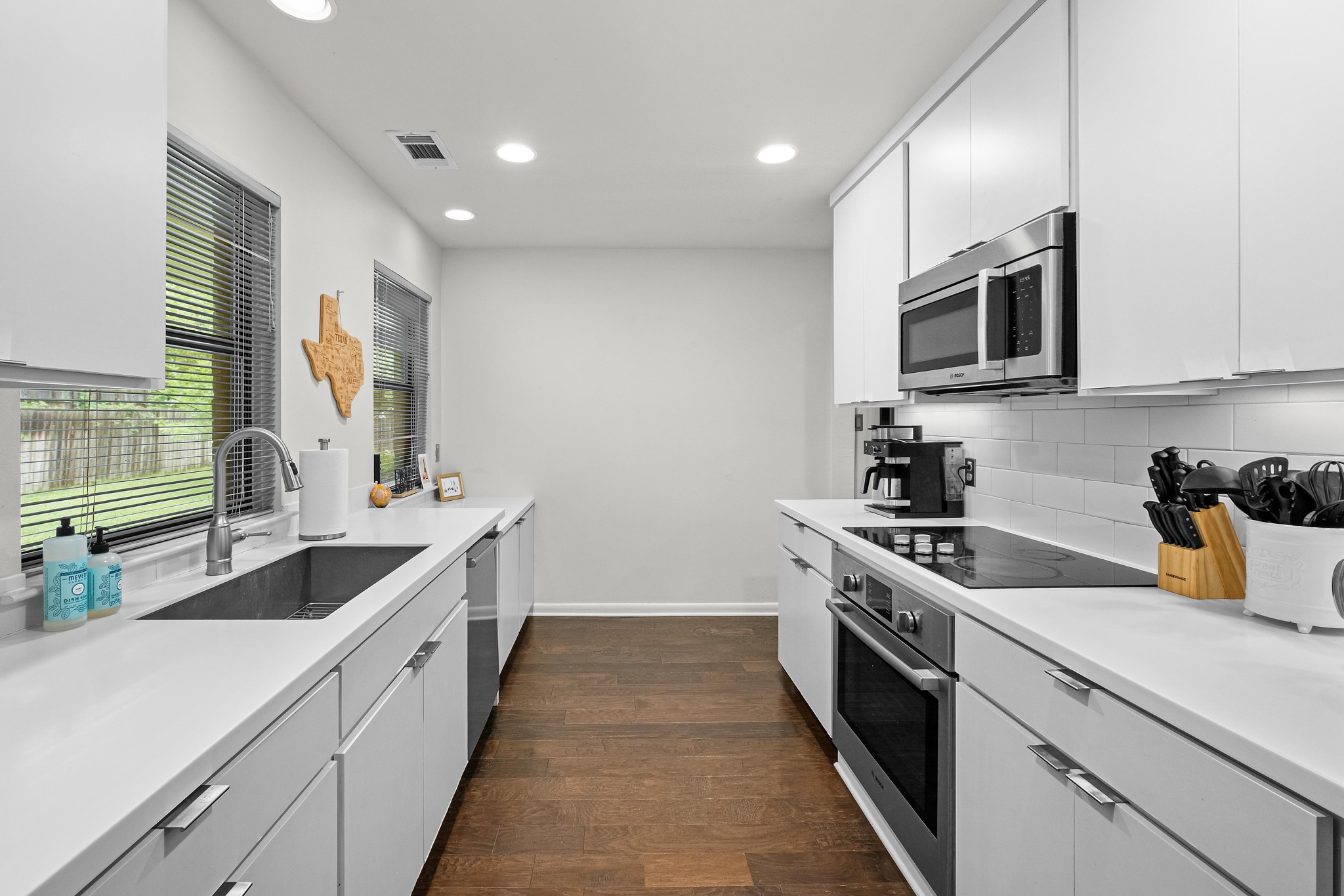 2802 Warren Street, Unit B Austin, TX 78703 - Photo 7 of 23 Galley kitchen featuring white cabinetry, light countertops, wood-finish flooring, recessed lighting, and stainless steel appliances