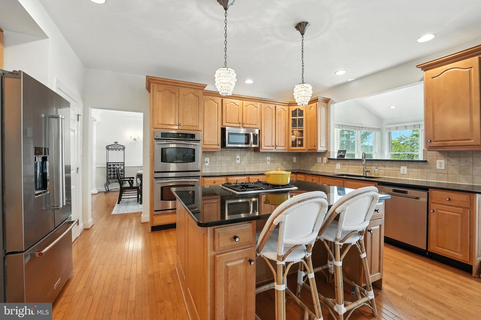 43152 Valiant Drive Chantilly, VA 20152 - Photo 2 of 44 a kitchen with stainless steel appliances granite countertop a stove a sink dishwasher a refrigerator white cabinets and wooden floor next to a window