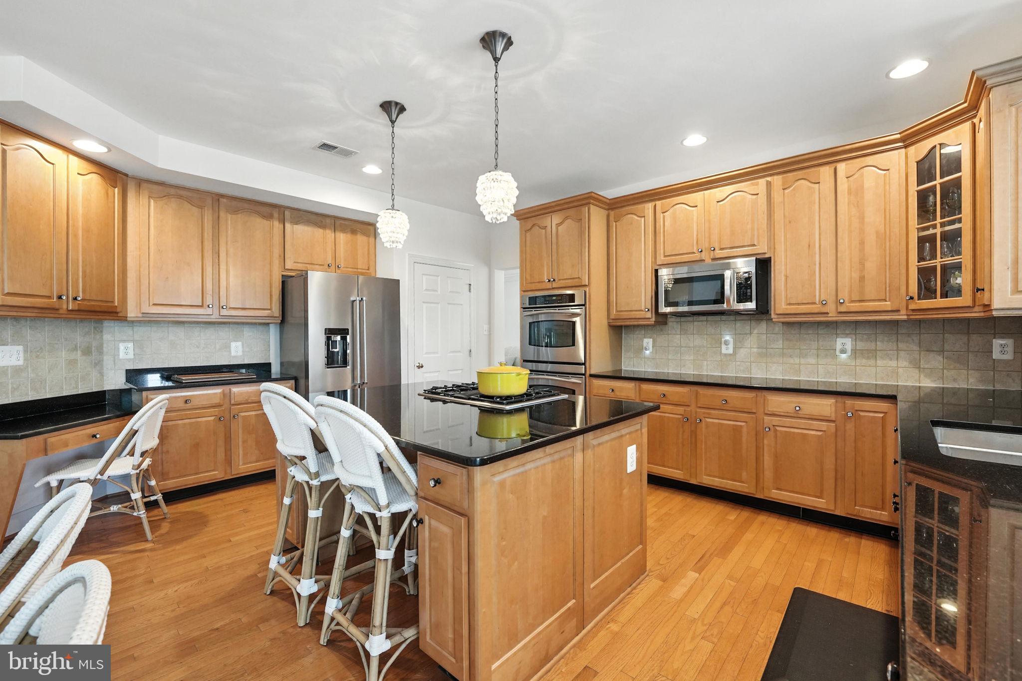 43152 Valiant Drive Chantilly, VA 20152 - Photo 10 of 44 a kitchen with stainless steel appliances granite countertop a stove a sink a microwave a refrigerator a dining table and chairs with wooden floor
