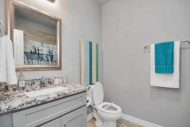 a bathroom with a granite countertop sink a toilet and mirror