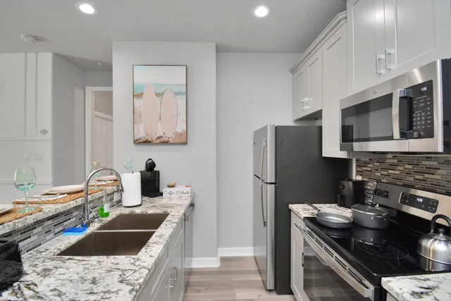 a kitchen with stainless steel appliances granite countertop a sink stove and refrigerator