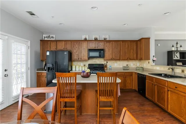 a kitchen with granite countertop a dining table chairs and a refrigerator